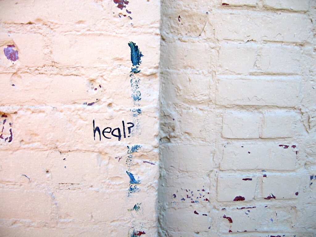 A white wall with the word heal? in between paint splatter
